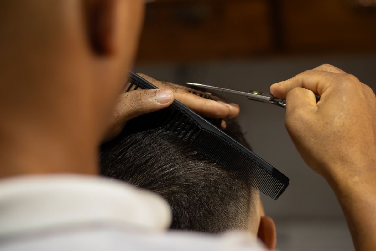 A barber mid-cut, unable to reach the phone